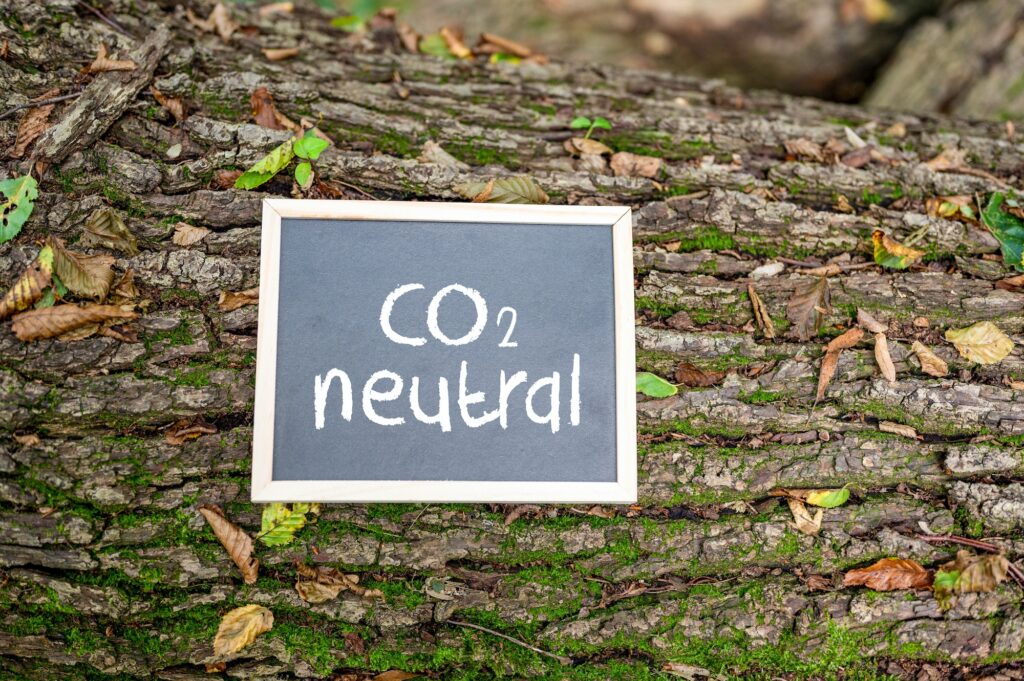 'CO2 neutral' written on a board on a tree trunk - carbon neutrality concept